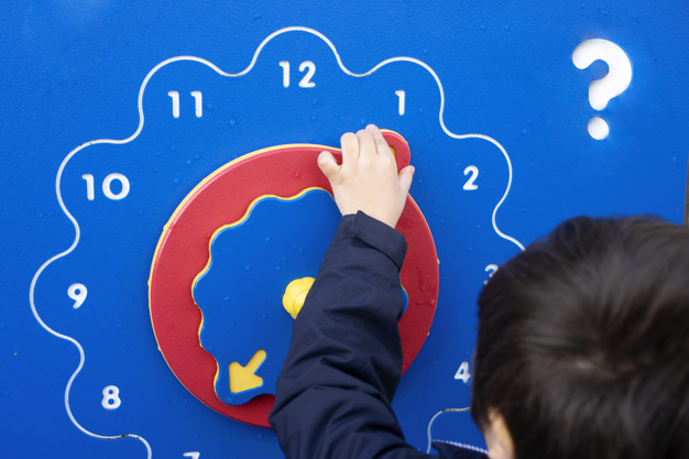 Rear view of little boy learning time with wooden clock at playground, Kid learning to tell time, Concept of learning by playing for children development